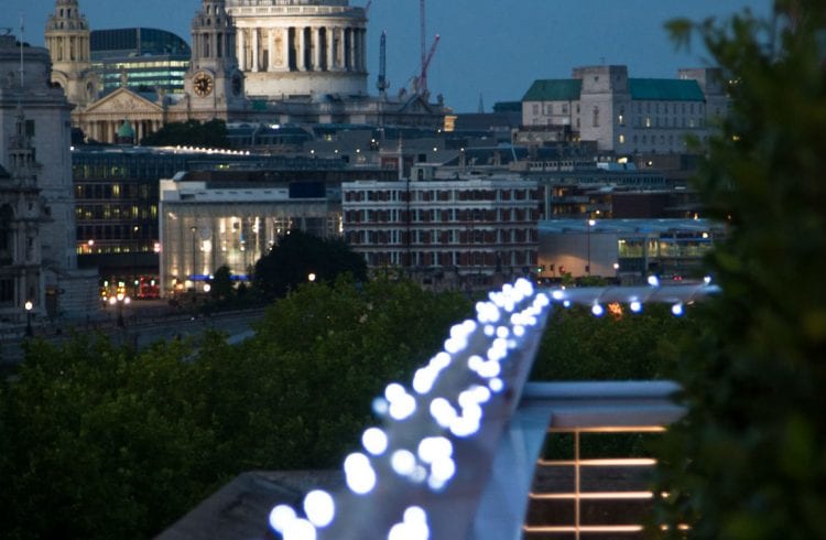 The Buffini Chao Deck event hire space: the terrace at night with fairy lights and views towards St Paul's