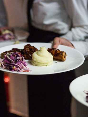 White-shirted waiters holding plates of roast beef dinner