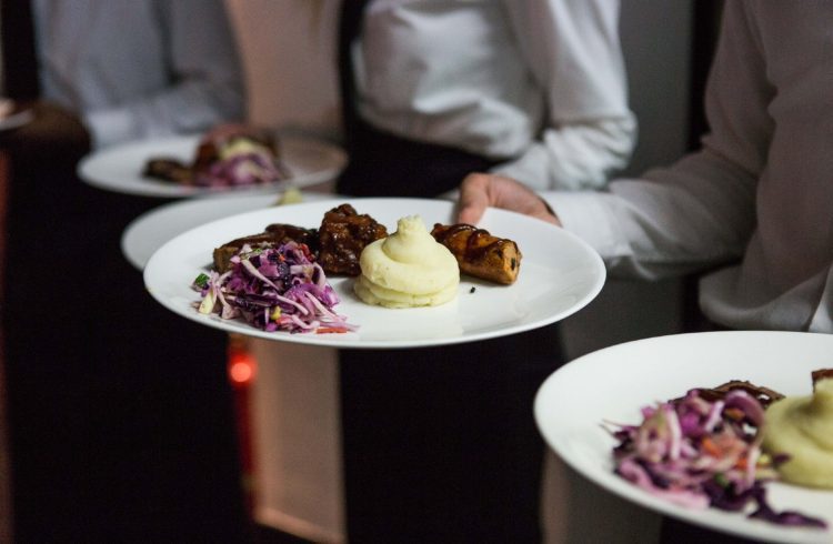 White-shirted waiters holding plates of roast beef dinner