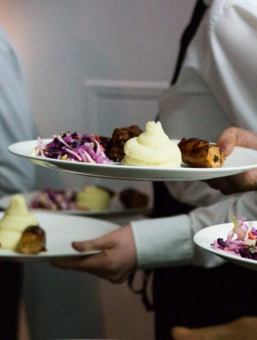 White-shirted waiters holding plates of roast beef dinner