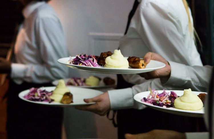 White-shirted waiters holding plates of roast beef dinner