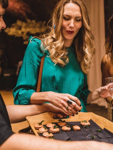 Canapes served by a waiter, holding a wooden tray, offering to two female customers