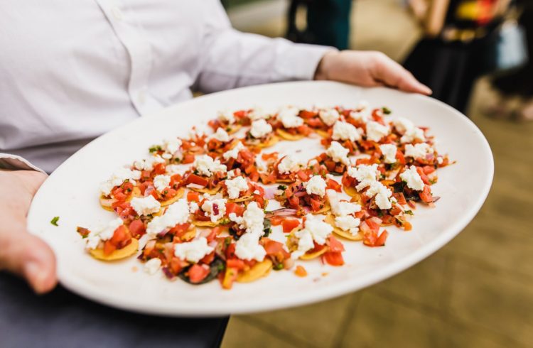 A white platter of canapes being held by a waiter