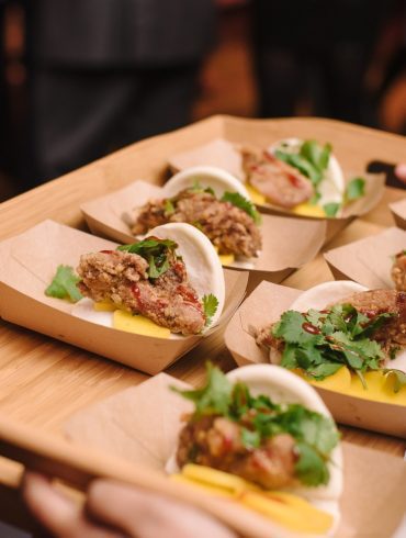 A wooden tray with 7 large canapes, each in individual carboard trays