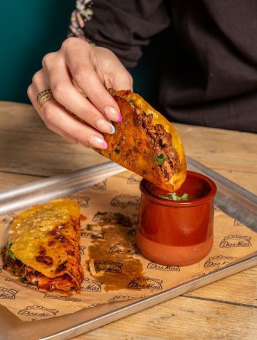 A taco being dipped in a pot of salsa