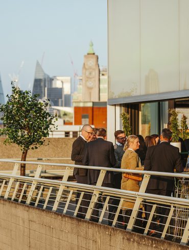 People standing on a terrace with the City of London skyline behind them