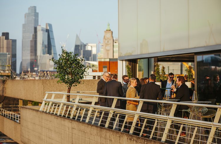 People standing on a terrace with the City of London skyline behind them