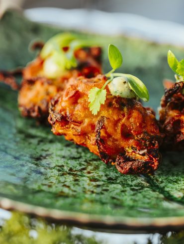 Canapes served on a china plate in the shape of a leaf.