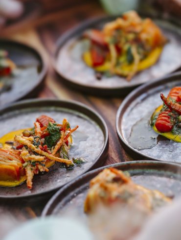 Small plates of food on a wooden tray.