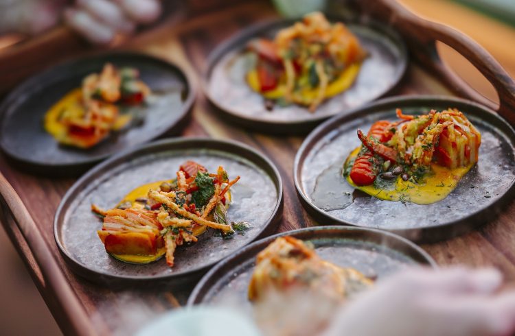 Small plates of food on a wooden tray.